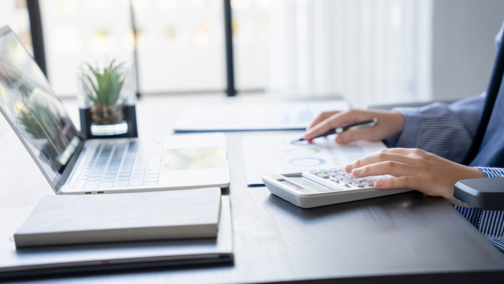 資料を見ながら電卓を打つ人の手元画像