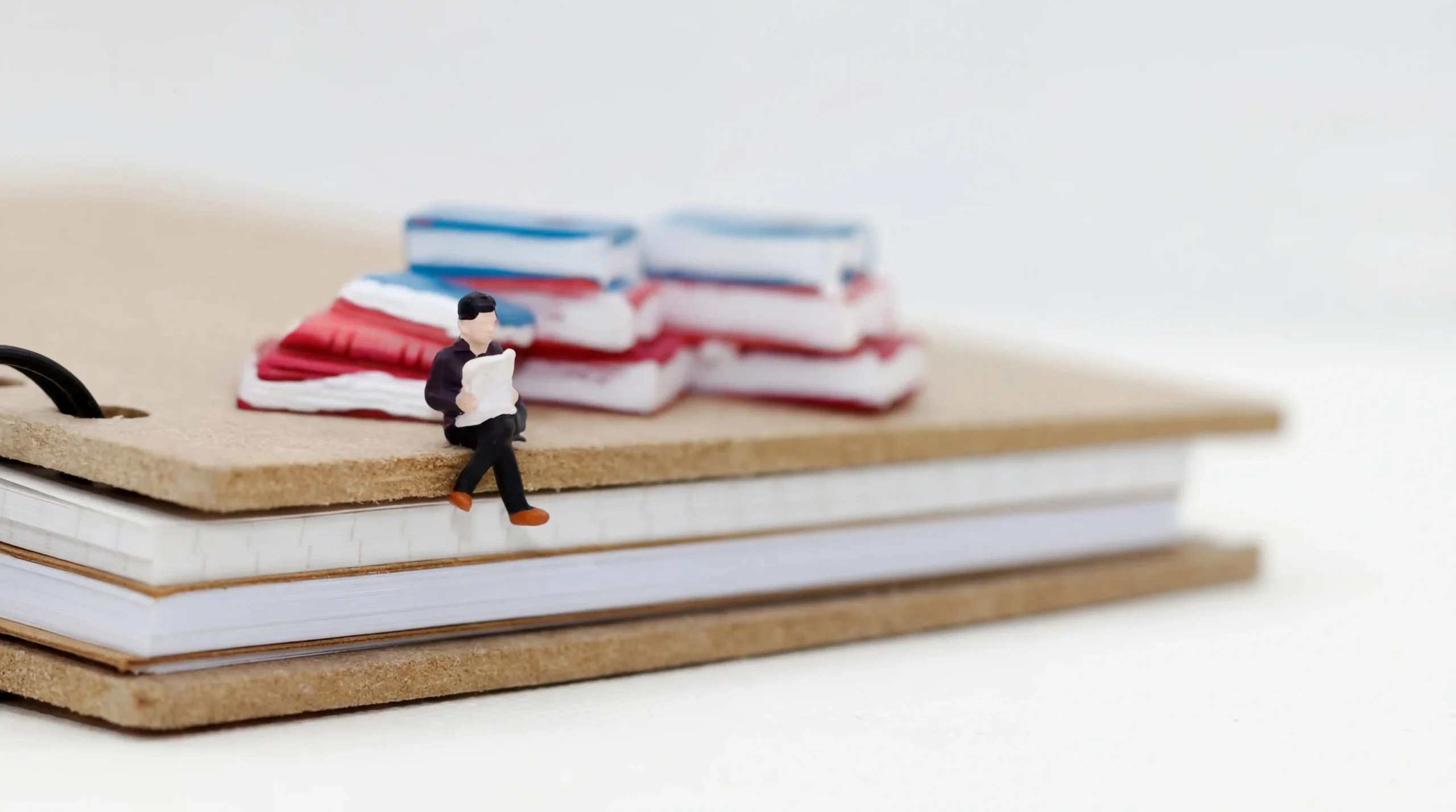 本の上に座って紙を見ている人形の画像